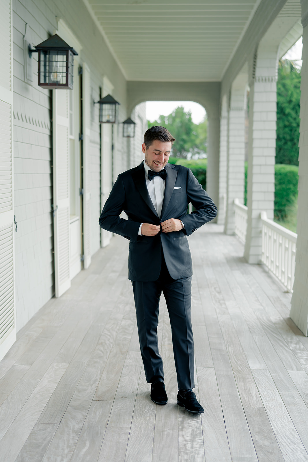 Groom buttoning tuxedo jacket and smiling. Ocean Course wedding.