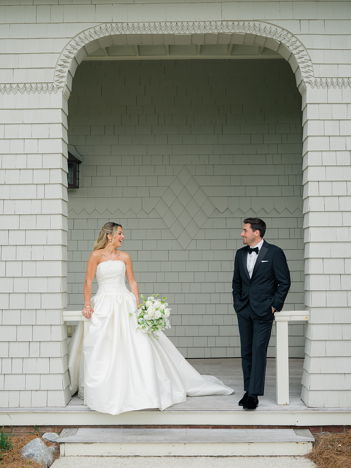 Ocean Course Spring Wedding. Bride and groom standing apart from each other on steps.
