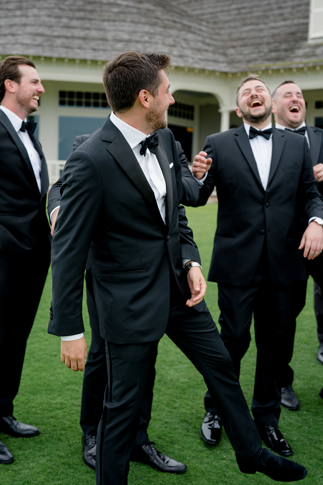 Best man laughing with groom. Candid ocean course wedding photos