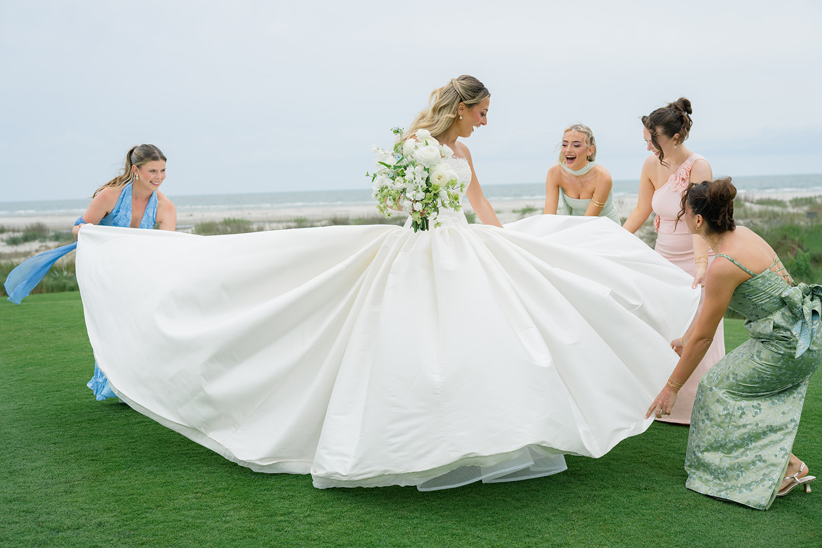Bride's friends help spread out wedding dress. Kiawah Island oceanfront wedding. 
