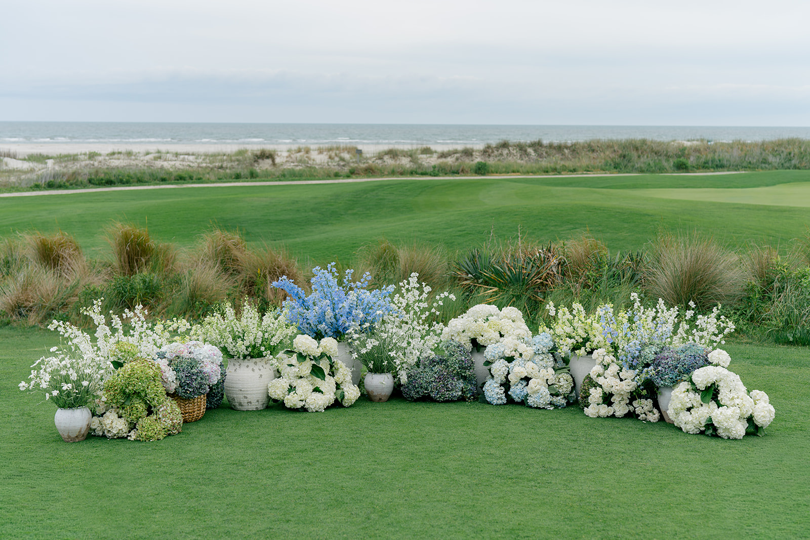 Low blue and white ceremony flowers with mismatched pots. Ocean Course spring wedding. 