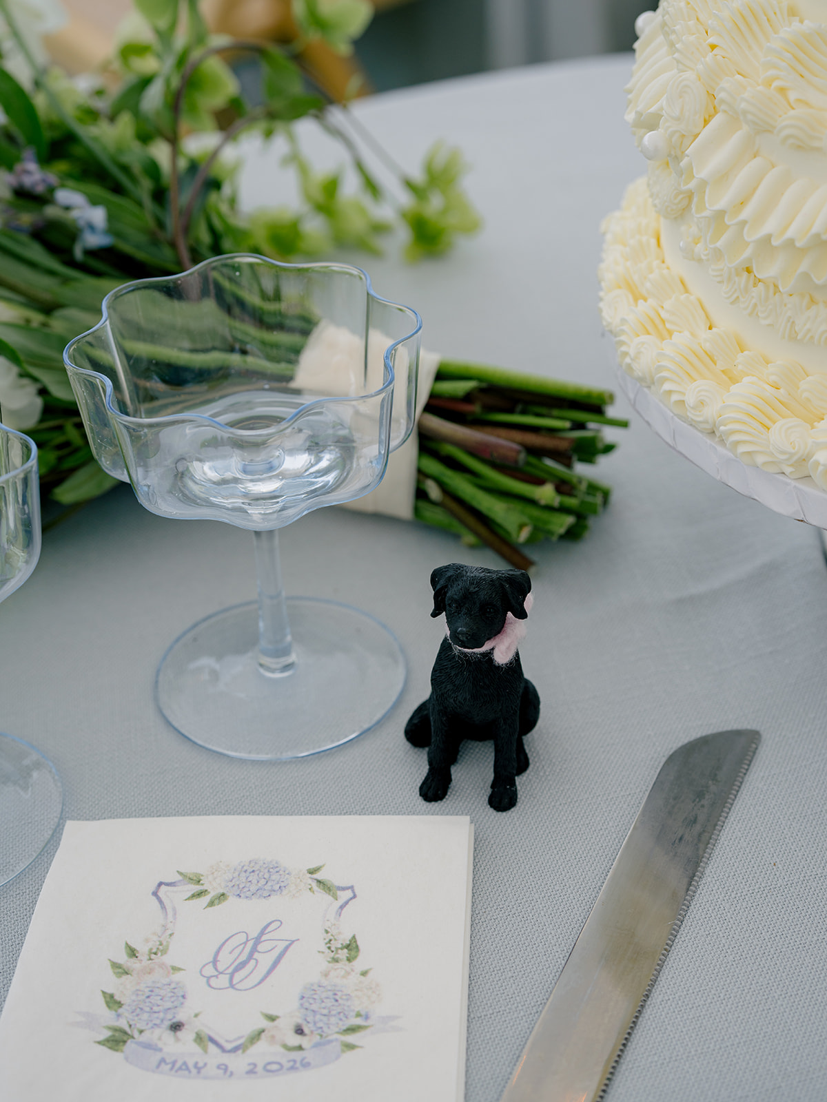 Black dog figurine with pink ribbon. Cake table at wedding reception. 