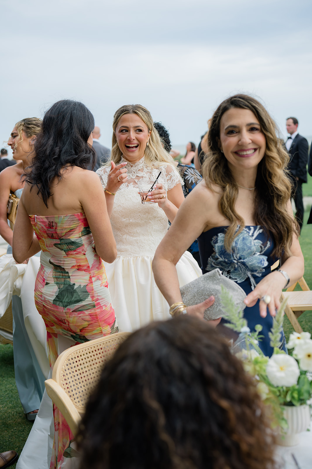 Bride laughing with friend with brides mom smiling at cocktail hour. 