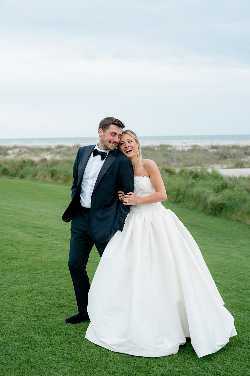 Bride holds grooms arm and laughs. 