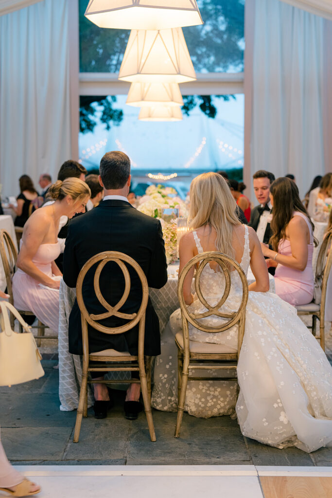 Bride and groom sit down at the head table for dinner. 
