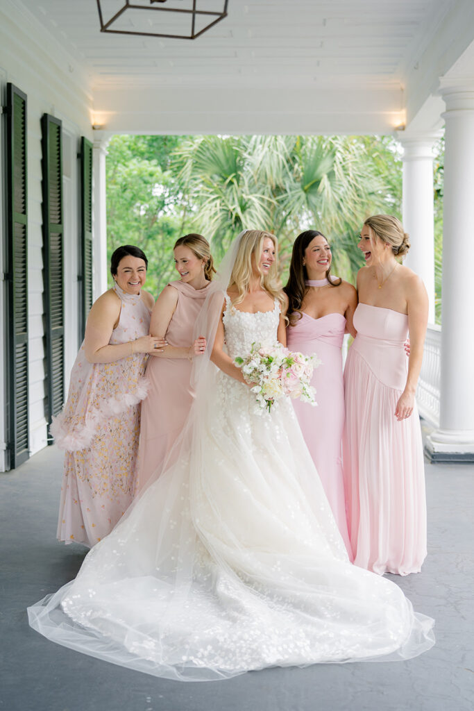 Bride and bridesmaids on the top porch. Bridesmaids in different pink dresses. 