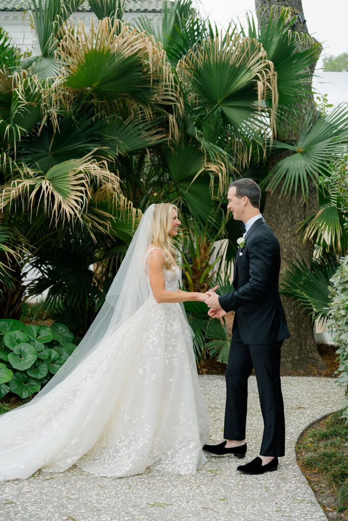 Bride and groom first look in front of palm leaves. 