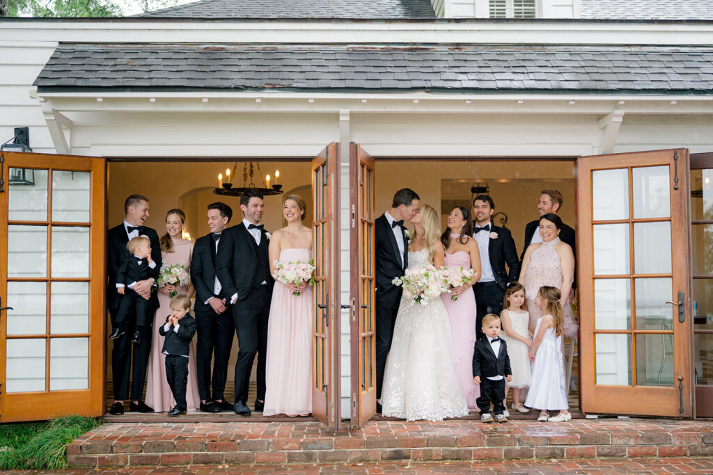 Bride and groom kisses with bridal party cheering. 