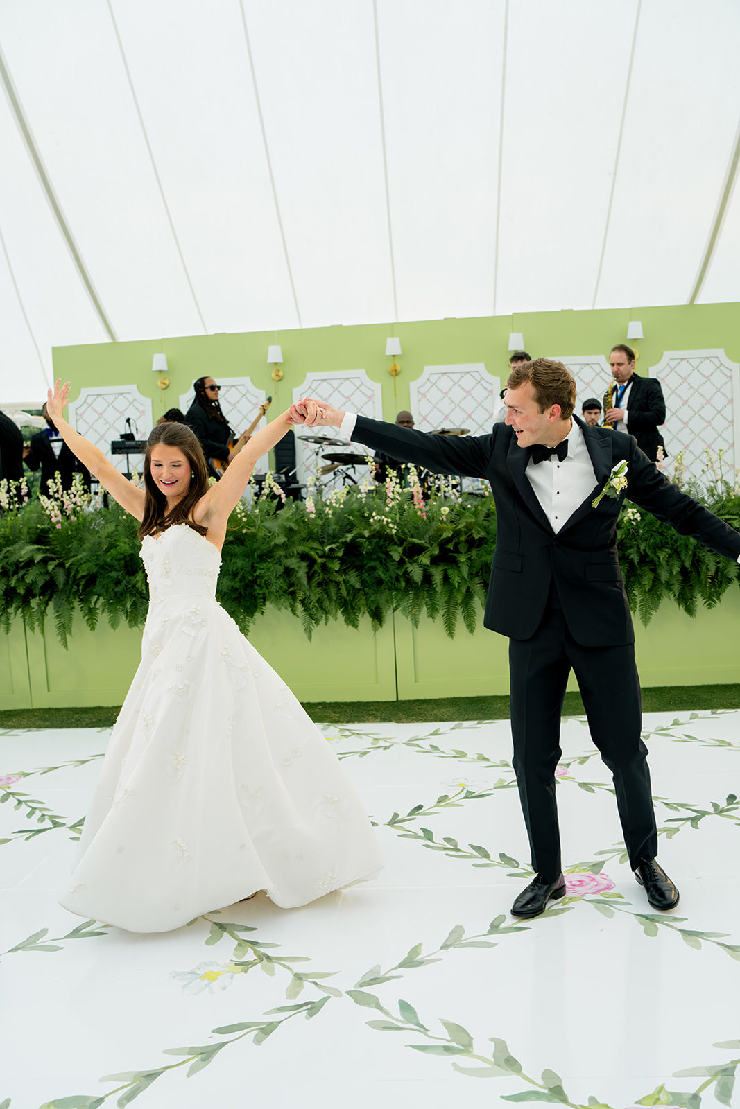 Bride and groom first dance on custom dance floor with white and pink floral design. 