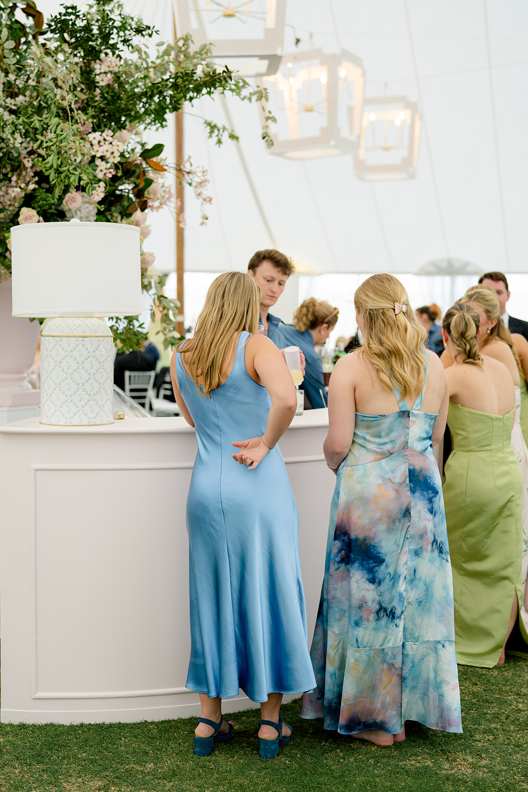 Wedding guests wait for a drink at pale pink wedding bar. 