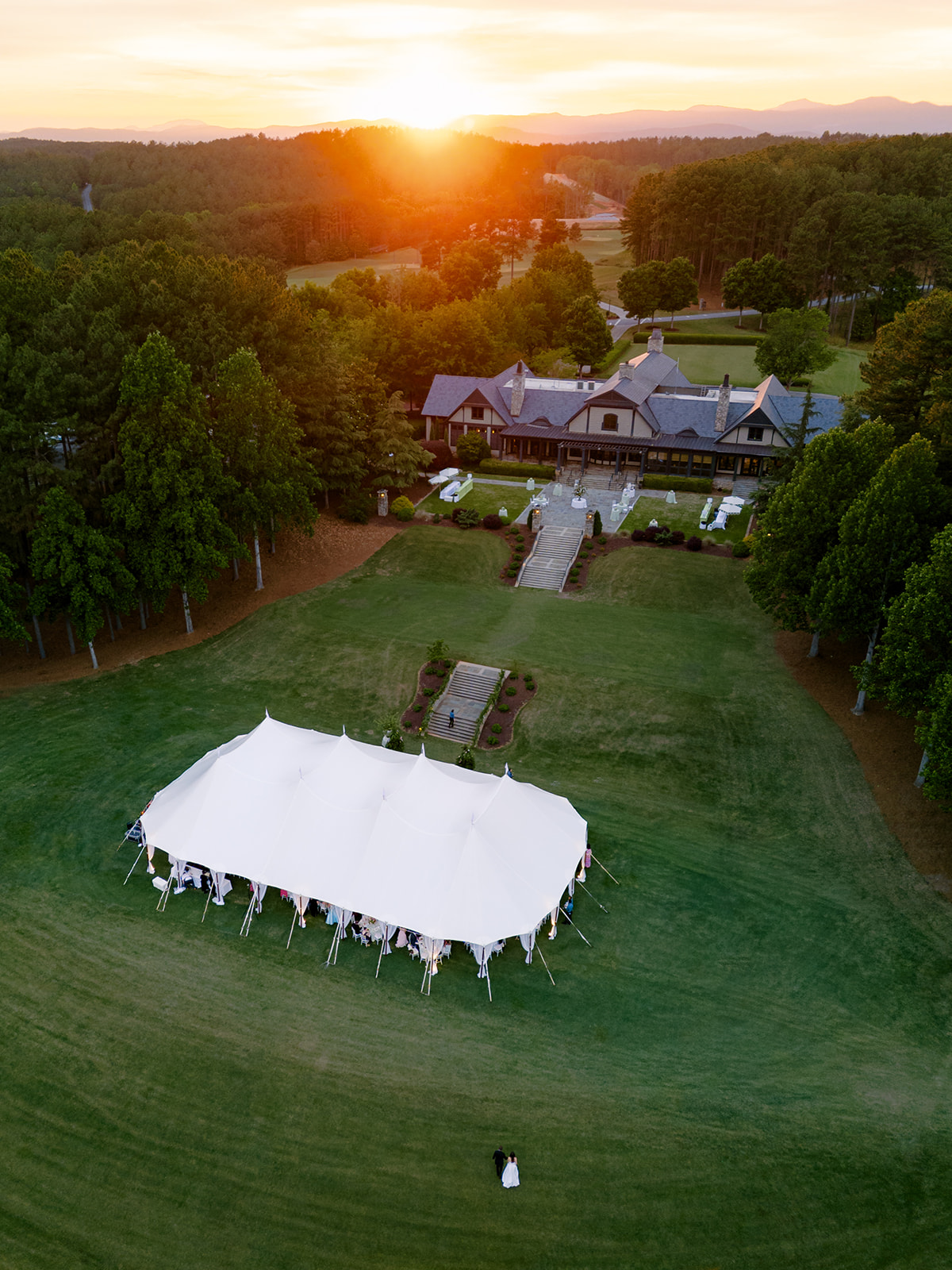 Bride and groom walk back to reception tent during sunset. Lake Keowee