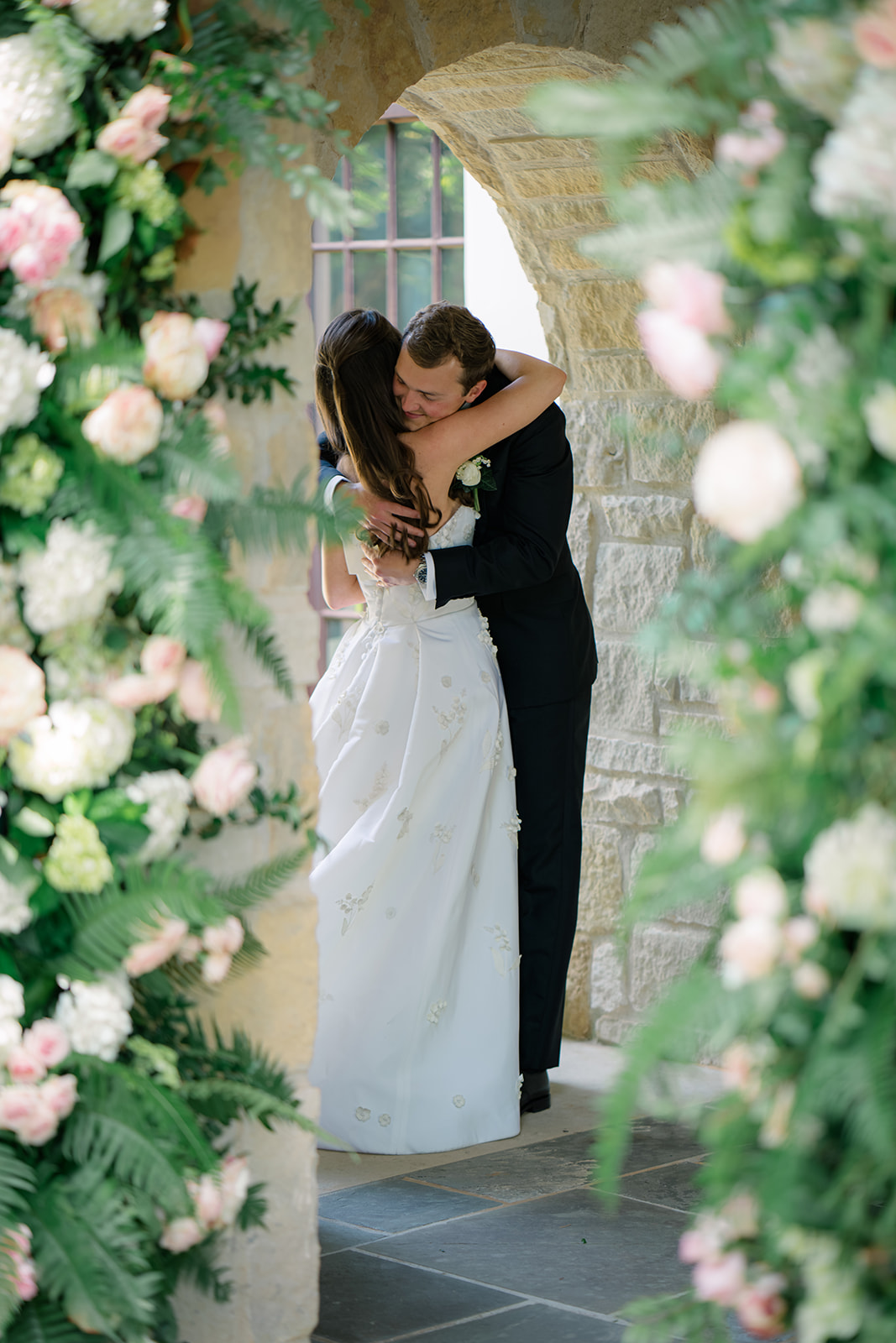 Bride and groom hug under the arch at the chapel.