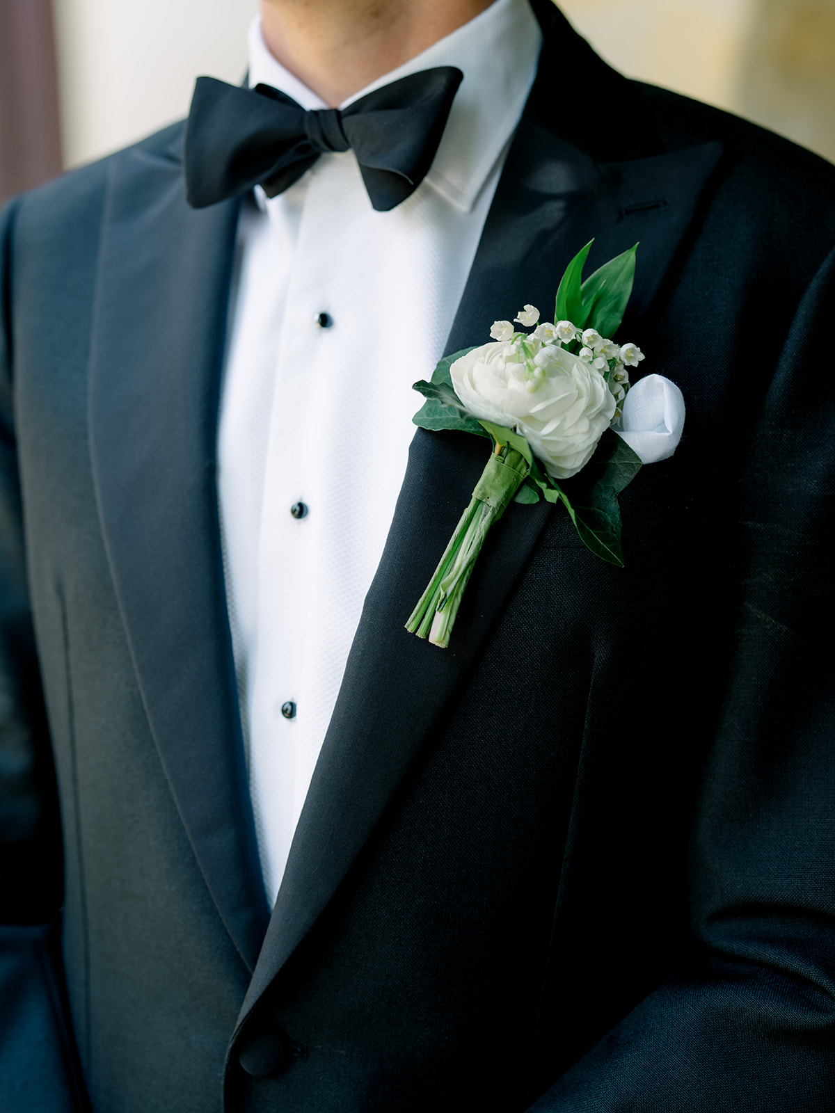 Groom in tuxedo with white boutonniere. 