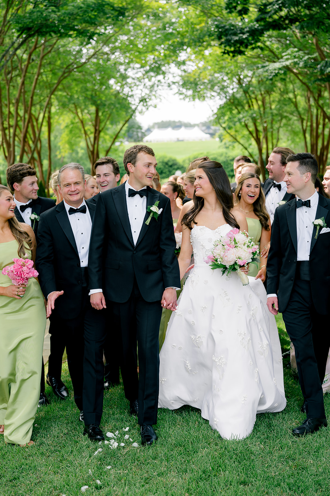 Bride and groom holding hands and walking with bridal party. 