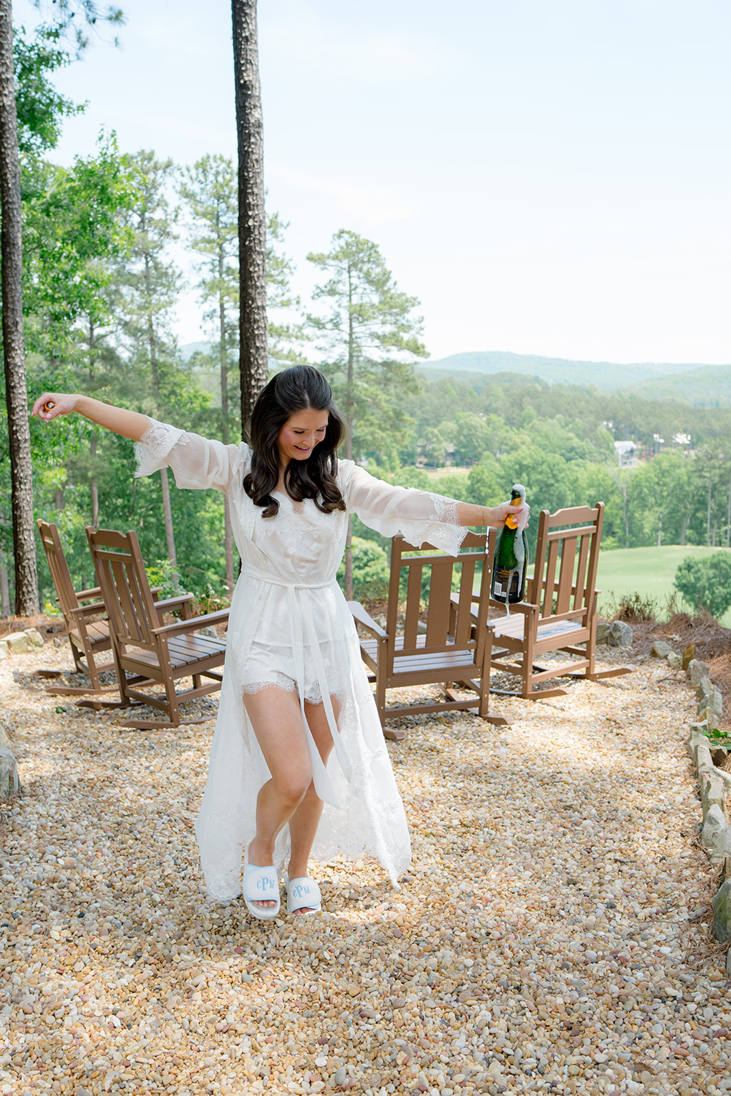 Bride pops champagne in her robe on the morning of her wedding.